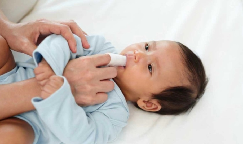 Dùng gạc thấm nước muối sinh lý và vệ sinh răng cho trẻ